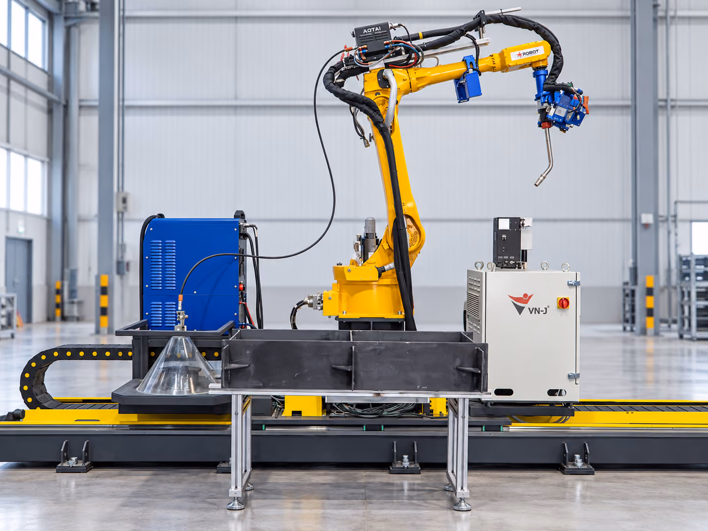 Hình minh họa hệ robot hàn trên ray với cánh tay vàng, nguồn hàn xanh và tủ điều khiển tại khu trưng bày.